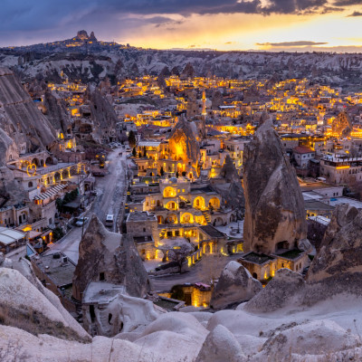 Goreme City at twilight, Famous tourist center of balloon fligths in Cappadocia, Turkiye, Aerial view twilight Goreme City from the mountain, Night view of Goreme, Cappadocia, Turkey.